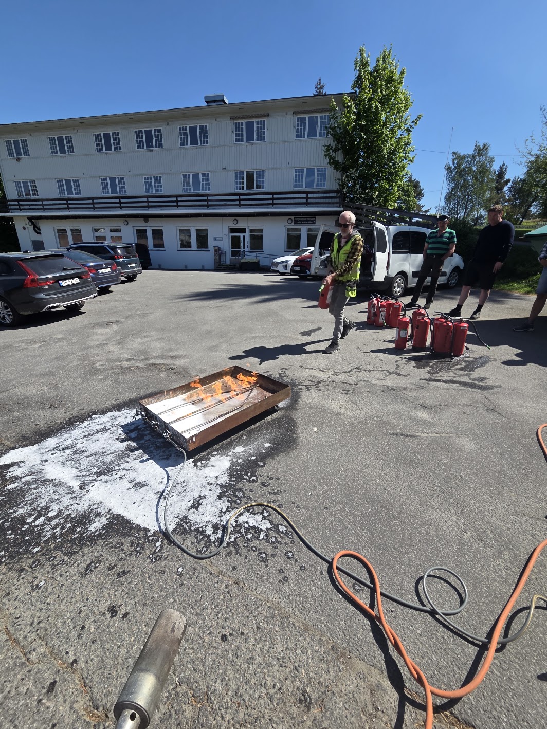 Gruppe med ansatte øver på slukking av ild på parkeringsplass