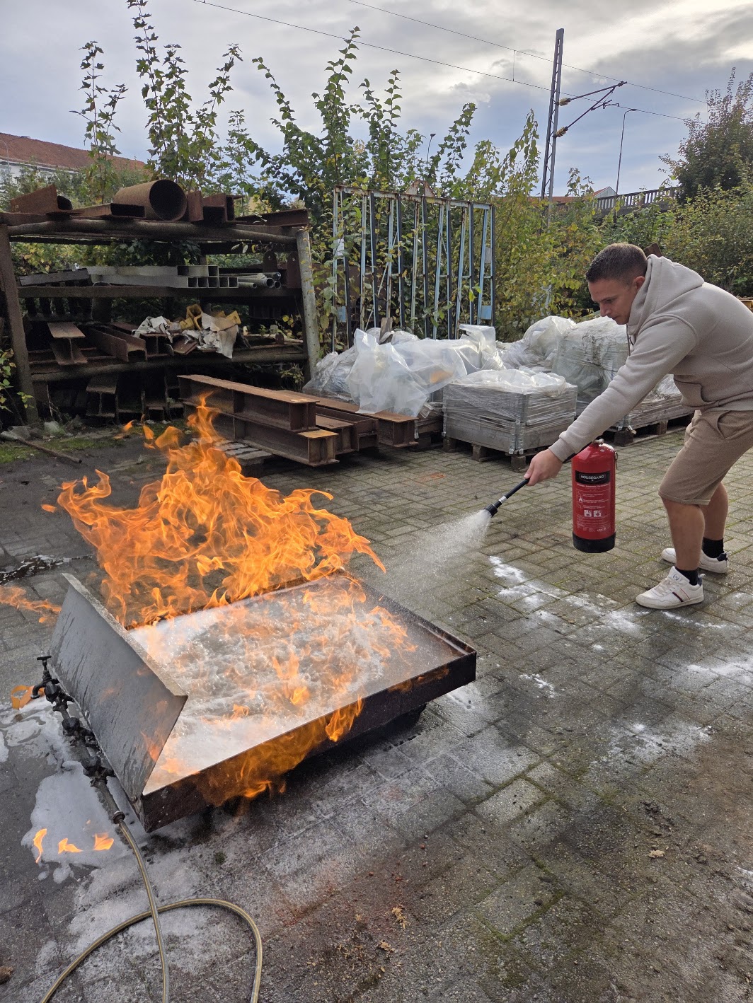 Deltaker i praktisk slukkeøvelse spruter pulverapparat mot levende flammer